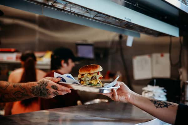 A server handing a food order to a customer across the counter.