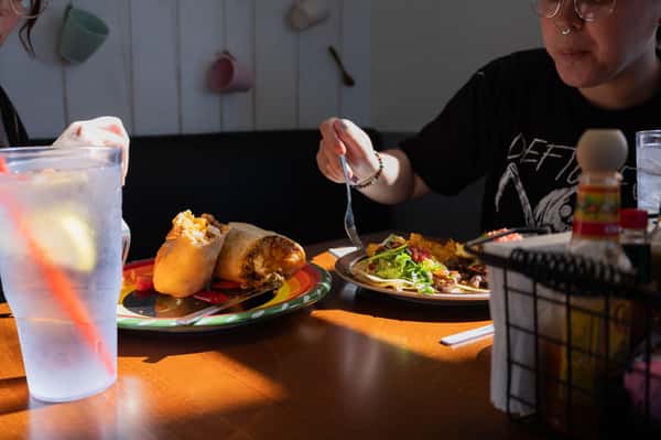 A person eating a wrap or sandwich with a side salad.
