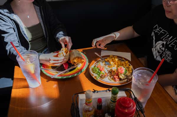 Diners at a table sharing a pizza or flatbread and iced drinks.