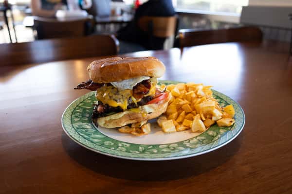 A cheeseburger and potato chips served on a green patterned plate.