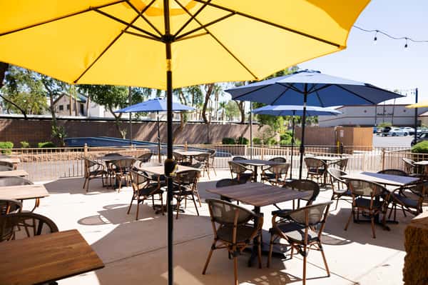 A view of the patio with empty tables and umbrellas.