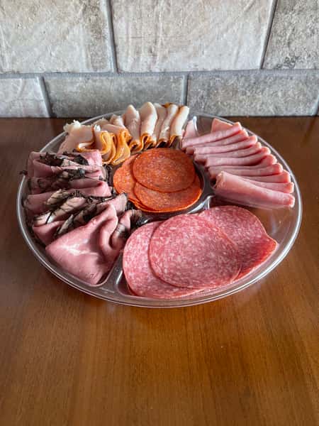 A divided platter of sliced ham, salami, pepperoni, turkey, and roast beef sits ready to serve, from Steak N' Cheese Please.