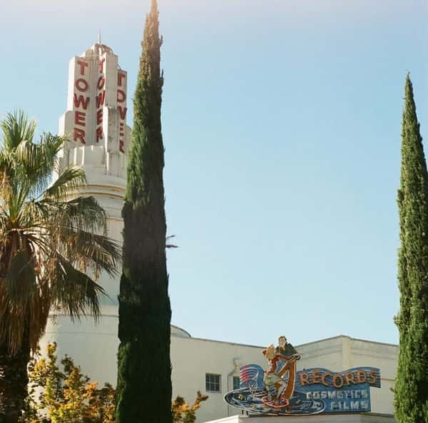 Art deco Tower District building with retro "Tower" sign, palm trees, and vintage-style sign for records, cosmetics, and films.