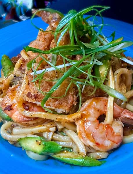 Garlic butter shrimp stir-fry with thick noodles, crispy soft-shell crab, and scallions, served with sautéed vegetables.
