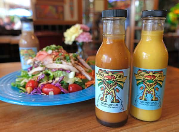 Colorful grilled chicken salad with cherry tomatoes and Tower Café's signature dressings, served in a vibrant, eclectic setting.