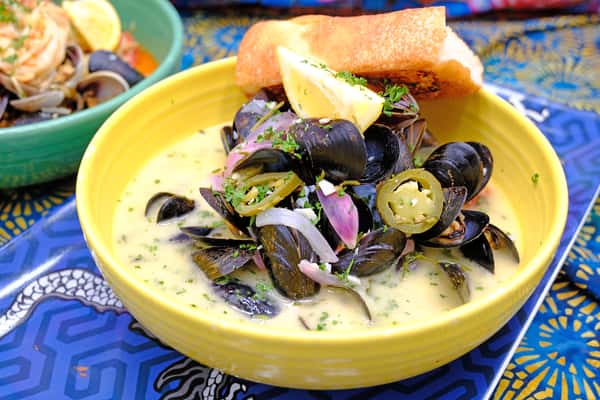 PEI mussels with white wine, garlic, tomato, jalepeno, parsley, onion, butter and cilantro. Garnished with crispy Thai basil and served with garlic bread