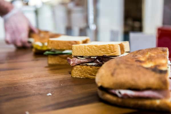 Fresh sandwiches being prepared on a wooden table, showcasing vibrant ingredients.