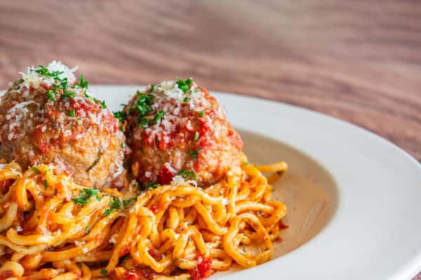 A generous serving of spaghetti tossed in rich marinara sauce and topped with tender homemade meatballs, grated Parmesan cheese, and fresh herbs. This classic Italian comfort dish is hearty, flavorful, and beautifully presented for a satisfying dining experience.