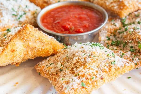Golden, crispy St. Louis-style toasted ravioli served with a side of rich marinara dipping sauce. Finished with grated Parmesan cheese and fresh herbs, this classic Italian appetizer offers a crunchy exterior with a warm, savory filling.
