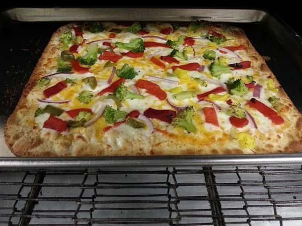 Grandma pizza pie topped with peppers and broccoli