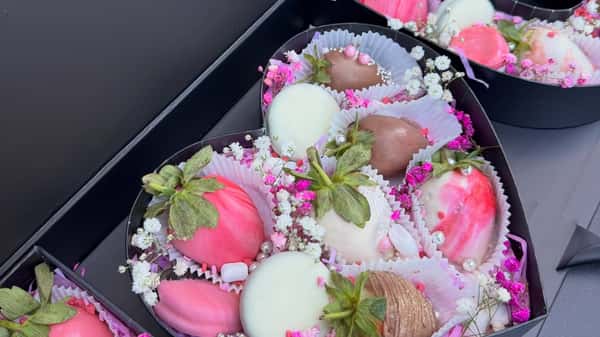 Assorted chocolate-covered strawberries in gift boxes with pink drizzle, white chocolate, and floral sprinkles