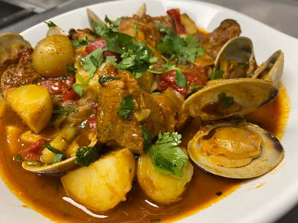 Pork and Clams Alentejo. A classic Portuguese dish with marinated pork, clams, garlic, potatoes and aromatics in a rich paprika infused white wine jus.