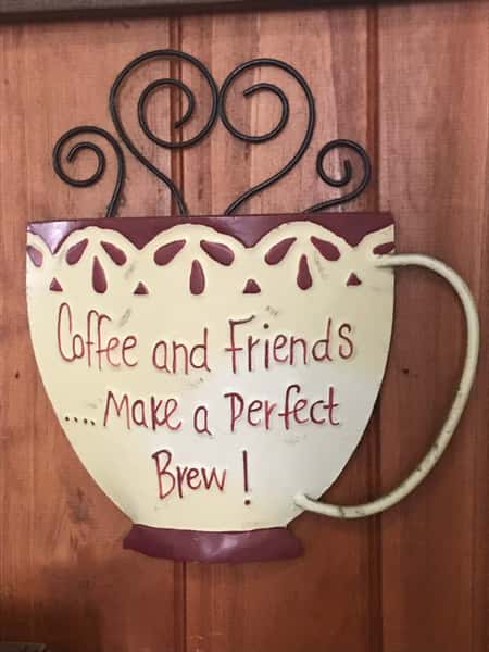 large sign shaped like a coffee cup and reading "coffee and friends bake a perfect brew"