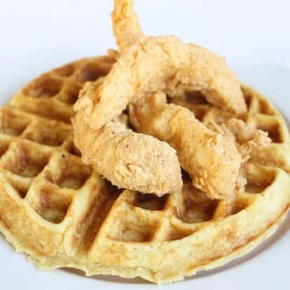 Crispy fried chicken tenders served on a golden waffle, classic chicken and waffles brunch dish.