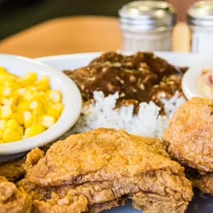 Southern comfort meal with crispy fried chicken, white rice with brown gravy, and buttery corn.