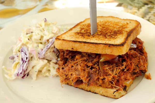 Toasted pulled pork sandwich with barbecue-style shredded pork and creamy coleslaw on the side.
