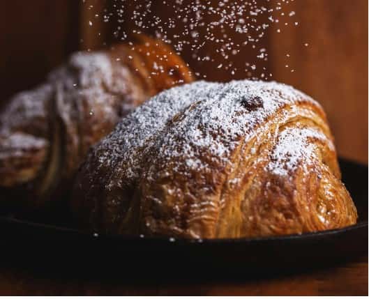 Plate of croissants covered in powdered sugar