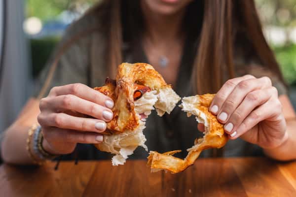 girl pulling apart a ham and cheese croissant