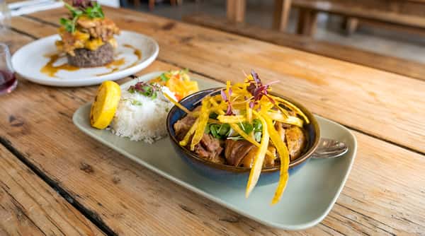 Braised pork bowl served on a long plate with a lemon wedge and vegetable garnish