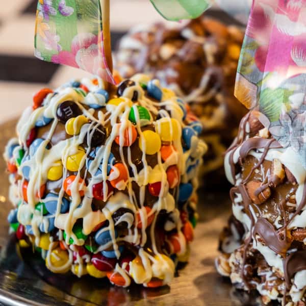 a candy apple with m&ms and white chocolate drizzle