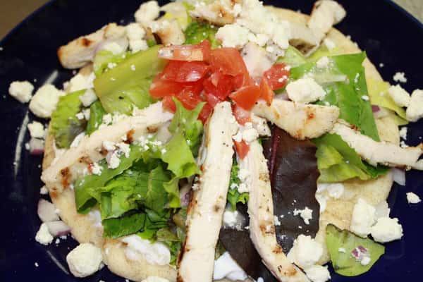 a salad with grilled chicken, feta cheese, and tomato
