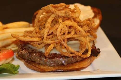 an open faced burger with onion straws on it