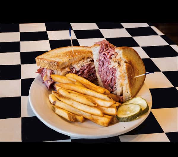 a reuben sandwich with a side of french fries and pickles