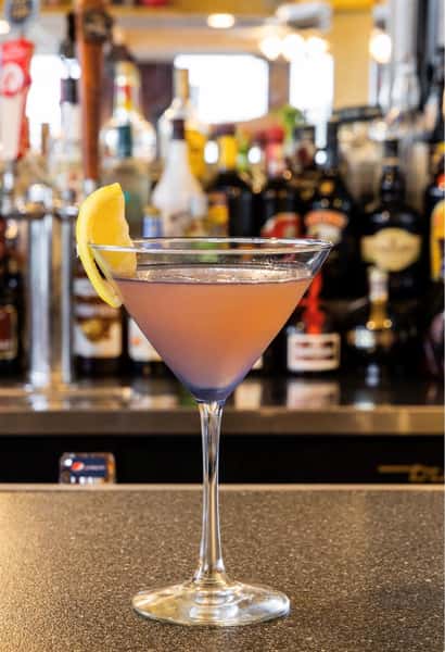 a pink martini on the bar with a lemon wedge