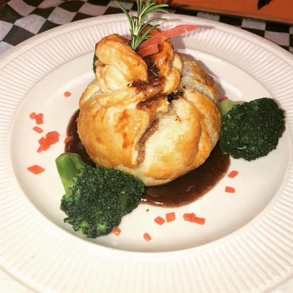 beef wellington on a plate with a side of broccoli
