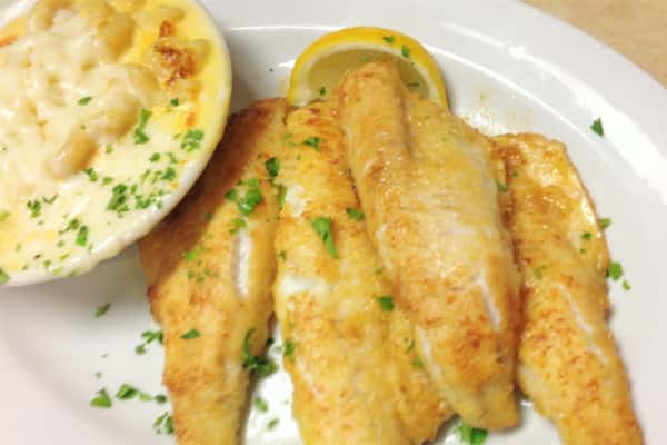 lemon chicken on a plate with two lemon wedges