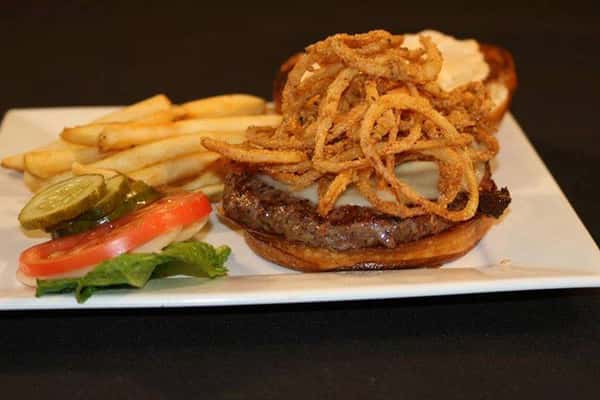 an open faced burger with onion straws and a side of french fries