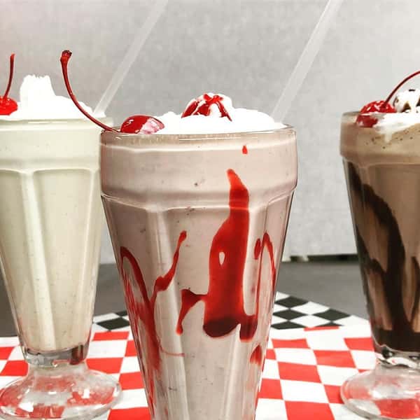 a vanilla, strawberry, and chocolate milkshake on a checkered table