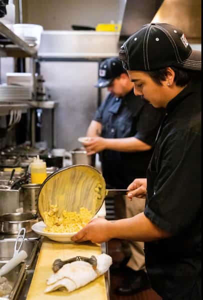 a chef pouring the mac and cheese from the pan onto the plate