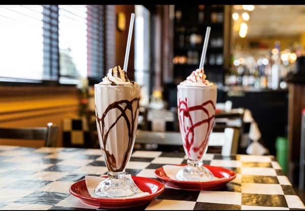 a strawberry and a chocolate milkshake on the counter
