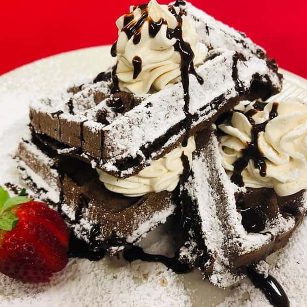 chocolate waffles with chocolate drizzle, whipped cream and a strawberry