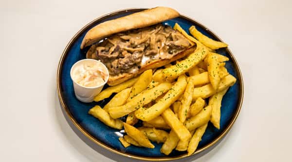 Philly cheesesteak sandwich with creamy mushroom sauce, fries, and coleslaw on a blue plate.