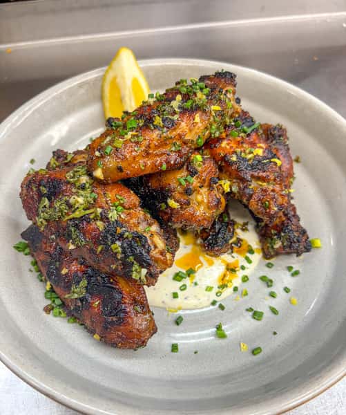 Grilled Greek Wings tossed with homemade garlic-lemon-herb sauce served over feta ranch.
