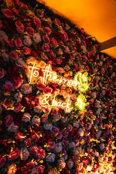 wall full of flowers with neon sign