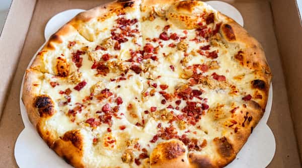 White pizza with melted mozzarella, crumbled bacon, and sausage.