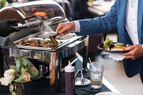 On-site catering buffet line inside the restaurant with hot trays of barbecue, sides, and serving utensils in San Antonio, TX