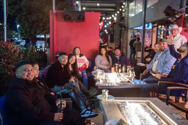 A group hanging out on the uncovered patio around a fire pit at Rock & Brews