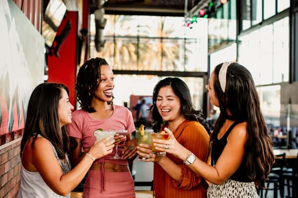Group of friends laughing and toasting drinks around a long table at a private group dining event in Grapevine, TX