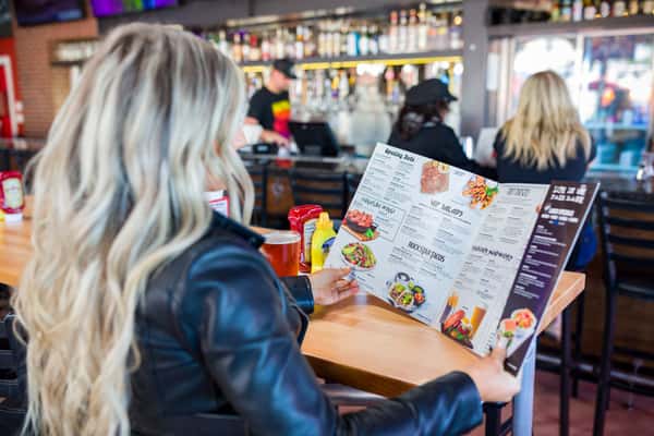 Woman seated at a restaurant table reading the menu in Grapevine, TX