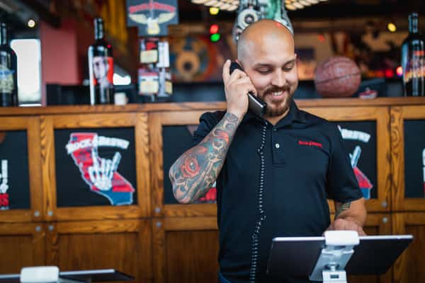 Team member at the host stand on the phone taking a large-party reservation in Oviedo, FL
