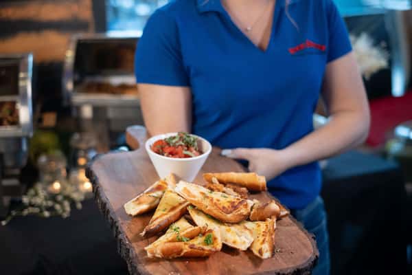 A woman carrying Bruschetta, one of the many delicious shareable passed appetizers made from scratch in Kissimmee, FL