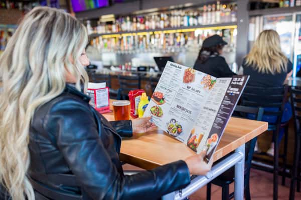 Woman seated at a restaurant table reading the menu in Orlando, FL