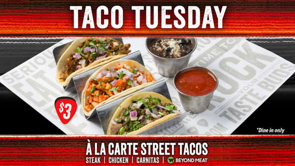 A vibrant Rock & Brews promotional graphic for Taco Tuesday featuring a trio of à la carte street tacos—steak, chicken, and carnitas—served in metal taco holders on branded parchment paper. Each taco is topped with fresh cilantro and diced red onions. To the right, small metal cups filled with black beans and red salsa complete the spread. A bold red guitar-pick graphic displays the $3 price. The design is framed with a red and black woven-style border, and the text highlights the offer: “À La Carte Street Tacos – Steak | Chicken | Carnitas | Beyond Meat.” The bottom corner notes “*Dine in only.”