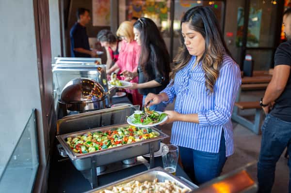 Coworkers in business attire mingling and eating at a corporate catering event in a private dining area in San Antonio, TX