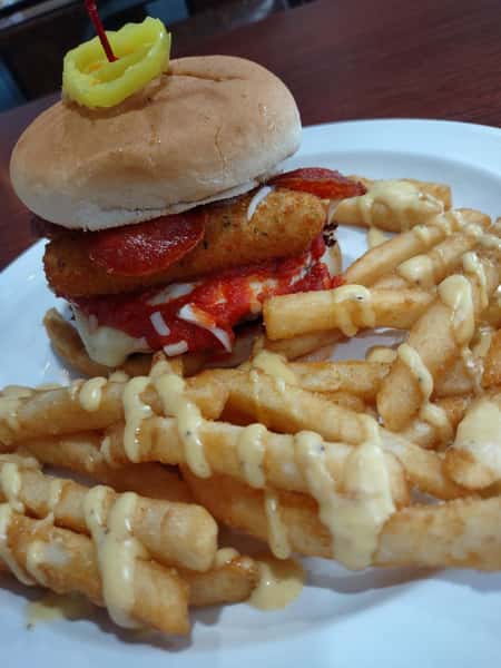 Crispy chicken sandwich with fries topped with cheese sauce