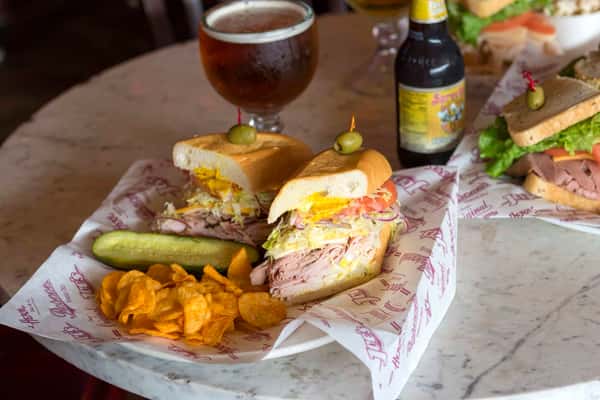 sandwich with pickle, chips and beer